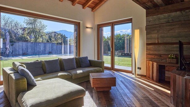 A spacious living room with a wooden ceiling, large sliding glass doors to a backyard, a green sofa, and a wooden coffee table. - Wonderful private villa with A/C, hot tub, WIFI, private pool, TV, patio and pets allowed (Colico)
