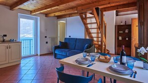 Uma sala de jantar com teto de madeira, um sofá azul e uma mesa posta para dois.