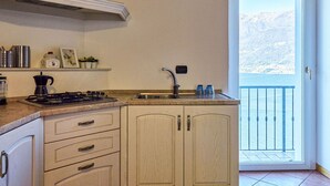 Cozinha com fogão a gás, pia e armários. Possui uma varanda com vista para montanhas.