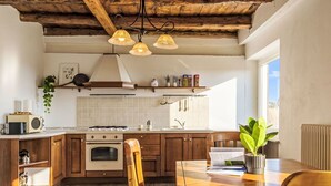A kitchen with wooden cabinets, a stove, a microwave, and a dining area with a table and chairs. - Beautiful apartment in villa for 6 guests with WIFI, TV, patio and pets allowed (Vendrogno)