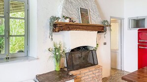 A rustic interior with a stone fireplace, a wooden shelf with plants, and a red appliance. - Lovely apartment in villa for 2 guests with WIFI, A/C, TV, terrace and pets allowed (Vendrogno)