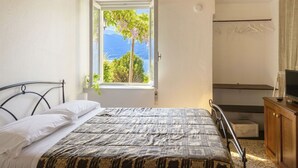 A bedroom with a bed, a window with a view of trees and mountains, a wooden ceiling, and a wooden cabinet. - Lovely apartment in villa for 2 guests with WIFI, A/C, TV, terrace and pets allowed (Vendrogno)