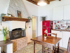 A kitchen with a brick fireplace, a red refrigerator, and a wooden dining table. - Nice apartment in villa for 2 people with WIFI, A/C, TV, terrace and pets allowed (Vendrogno)
