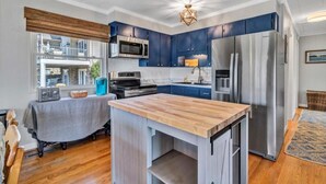 A modern kitchen with a central island, stainless steel appliances, and blue cabinetry. - Surfside - Dock with bar area / Gentle lot / Cozy Retreat (Moneta)
