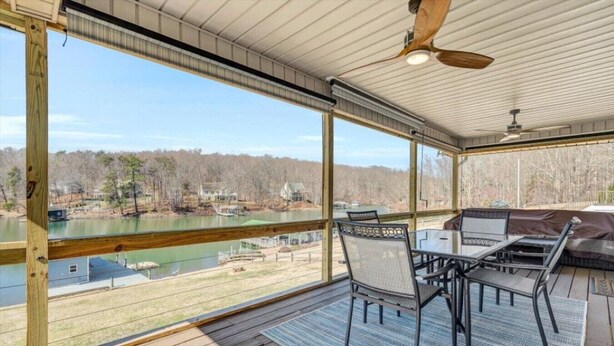 A covered outdoor area with a table and chairs, overlooking a body of water and a forested area. - Surfside - Dock with bar area / Gentle lot / Cozy Retreat (Moneta)