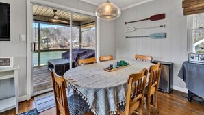 A dining area with a round table, wooden chairs, and a ceiling light. - Surfside - Dock with bar area / Gentle lot / Cozy Retreat (Moneta)