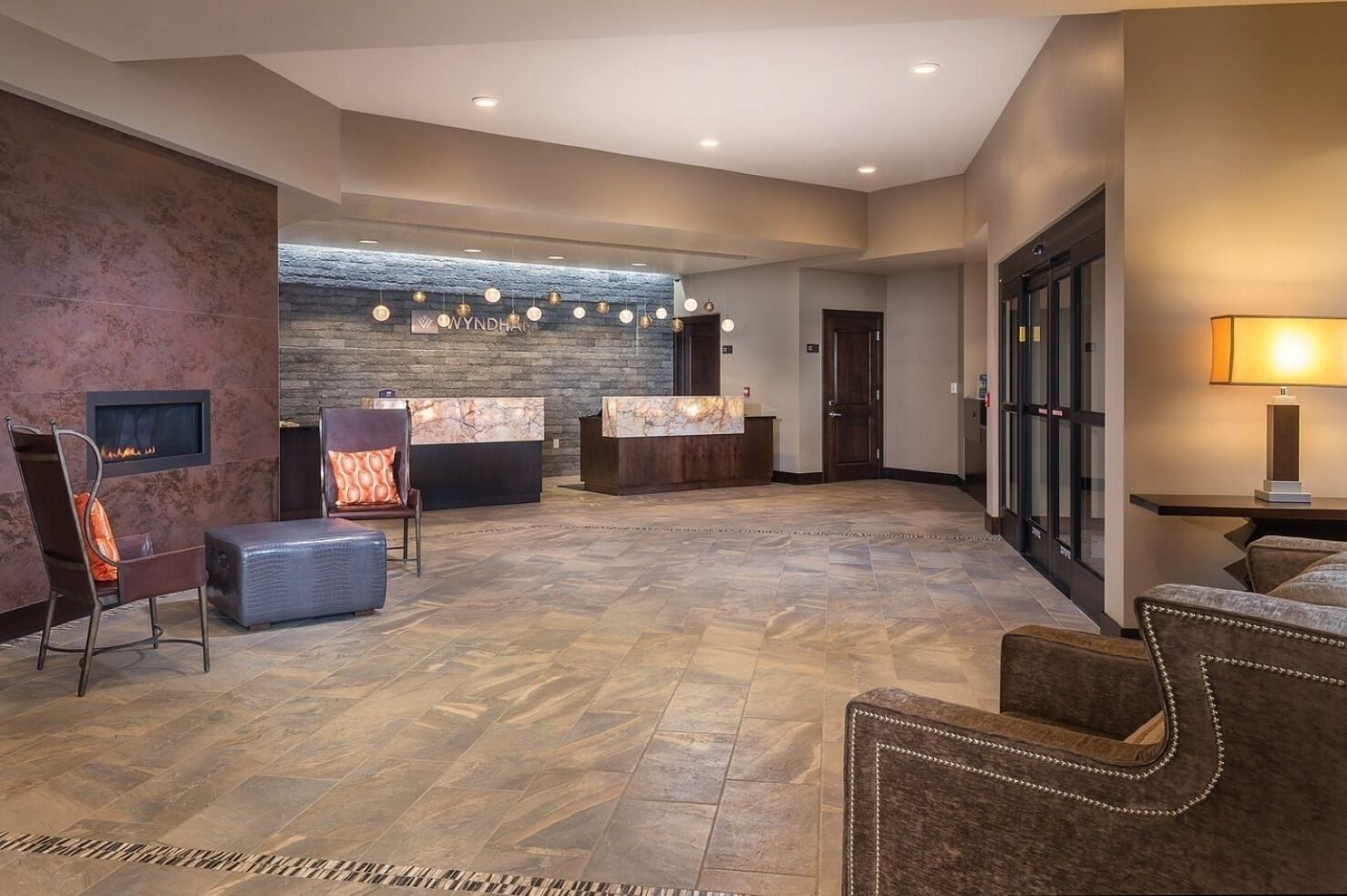 A lobby with a reception desk, seating area, and a stone wall with hanging lights.