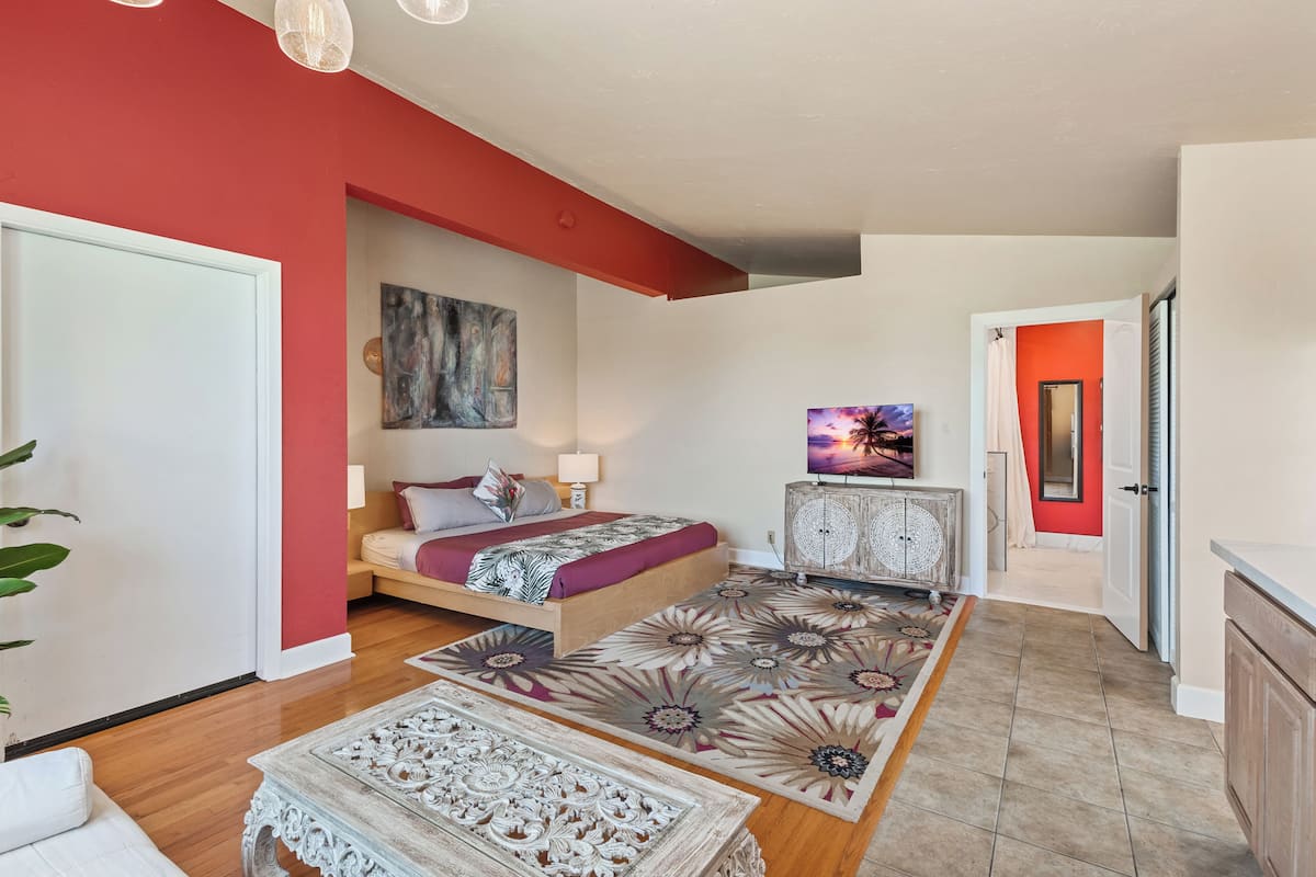 A bedroom with a bed, a nightstand, a dresser, and a painting on the wall.
