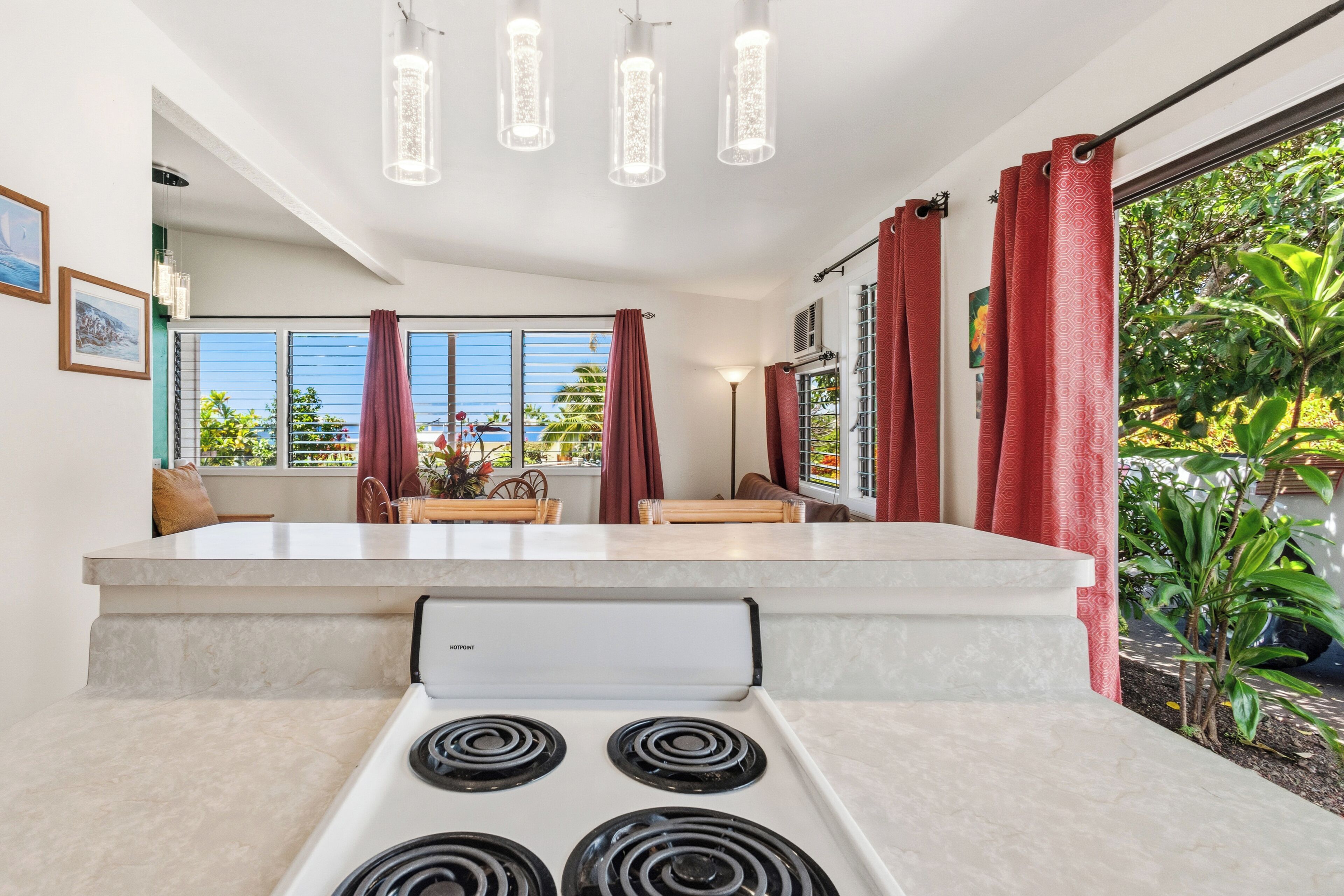 Una cocina moderna con estufa integrada, ventanas amplias con cortinas y vistas a la vegetación.
