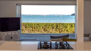 A modern kitchen with a large window overlooking a marina. - Driftwood Beach House with Spa Pool (Waiheke Island)