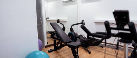 A gym with exercise equipment, a blue exercise ball, and a mirror on the wall.
