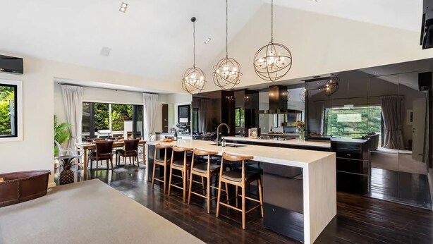 Une cuisine moderne dotée d’un îlot central, de tabourets de bar et de luminaires suspendus.