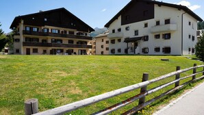 Un edificio con numerosi balconi e un cortile lastricato di erba.