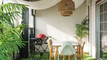 Un petit espace extérieur aménagé avec une table et des chaises, un barbecue et des plantes en pot.