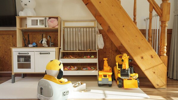 Een kinderspeelruimte met speelgoed, een keukentje en een houten trap.