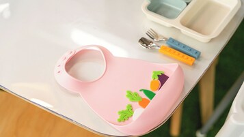 A pink baby bib with vegetable designs on a table.
