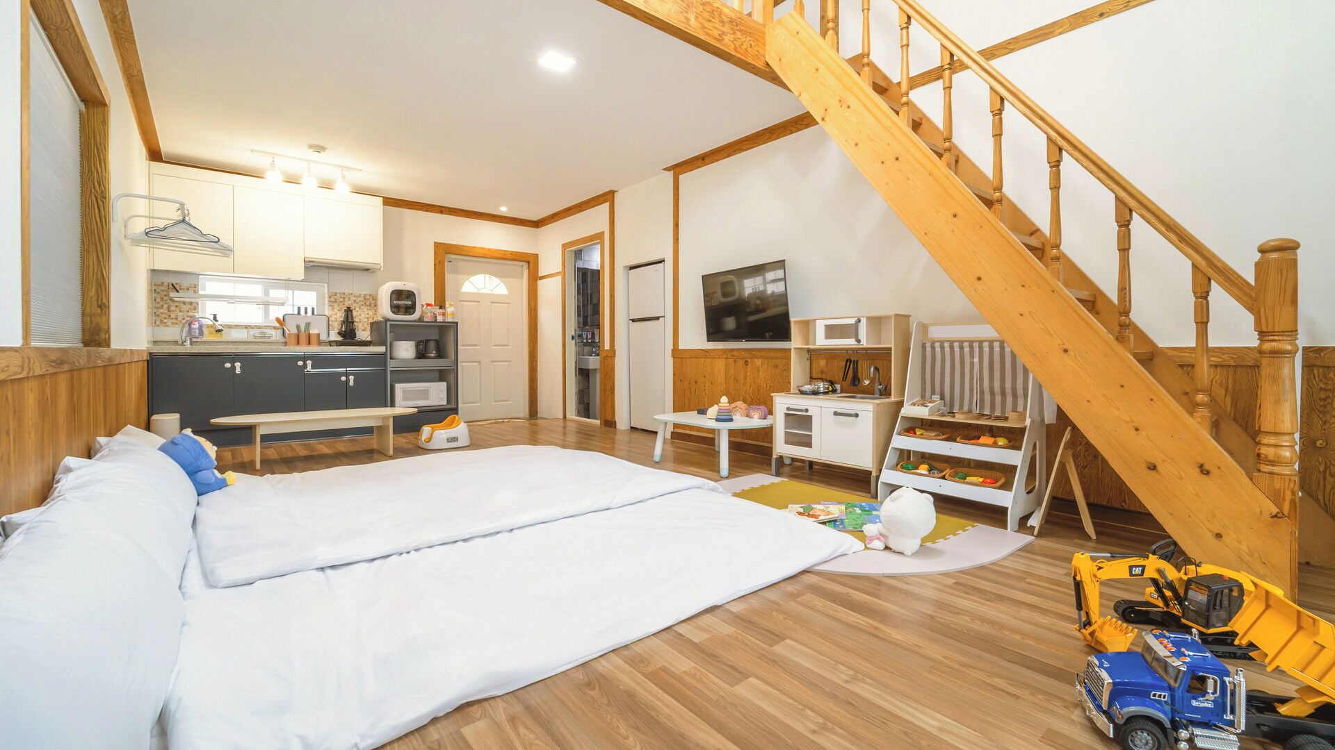 Un dormitorio con cama, escritorio, silla, televisor y escalera.
