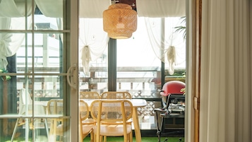 An indoor dining area with wicker chairs, a table, and a grill.