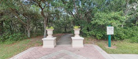 A paved pathway leading to a sign for Emerald Island Resort Nature Walk.