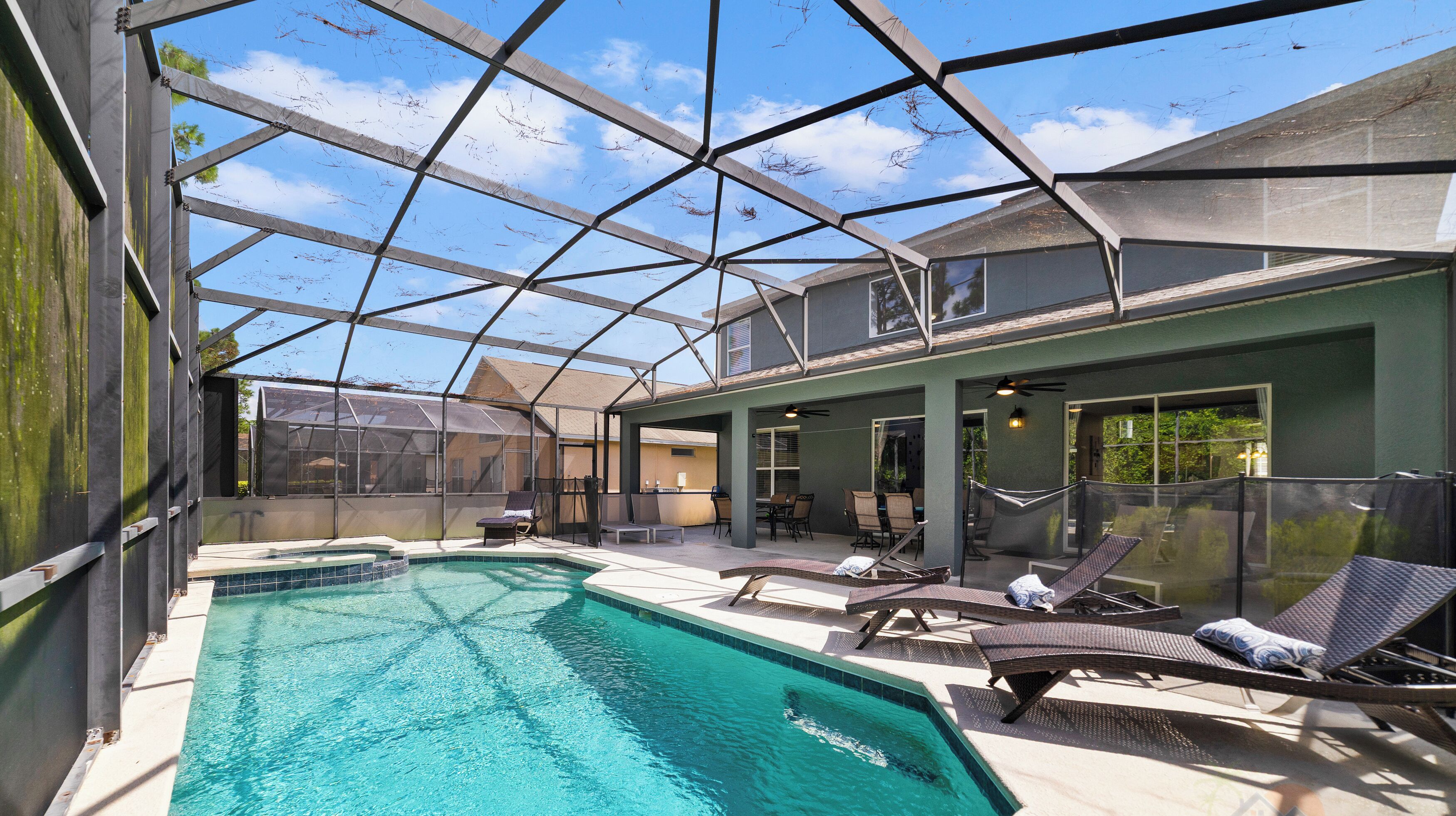 A covered swimming pool with lounge chairs and a patio area.
