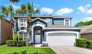 A two-story house with a garage, palm trees, and a well-maintained lawn.