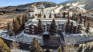 Un hôtel avec une piste de ski en arrière-plan, entouré d’arbres couverts de neige.