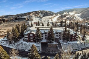 Un albergo con una pista da sci sullo sfondo, circondato da alberi innevati.