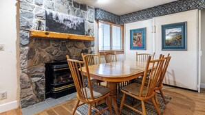 Un coin repas avec une cheminée en pierre, des chaises en bois et une table.
