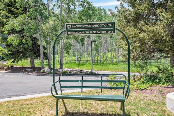Un banc avec une plaque indiquant « Snow Flower Park City, Utah » et « Télésiège Motherlode, construit entre 1980 et 2015 ».