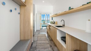A modern kitchen with wooden cabinetry, a white countertop, and a view to the outside.