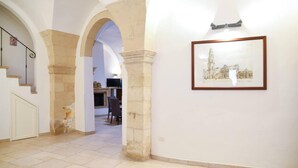 A hallway with a stone archway, a framed picture on the wall, and a staircase with a metal railing. - Holiday Home Sleeps 6 in the Historic Center of Le (Lecce)