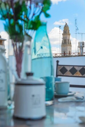 Une table avec une théière, un verre et une bouteille, et en arrière-plan, on aperçoit une tour.