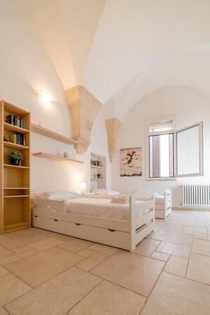 Une chambre avec un grand lit, une bibliothèque en bois, un radiateur et une fenêtre.