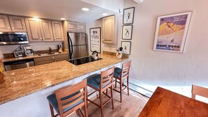 A modern kitchen with granite countertops, stainless steel appliances, and wooden chairs. - Vail Mountain Views From Upper Level 2BR Condo - In Unit Washer/Dryer (Vail)