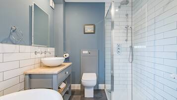 A modern bathroom with a bathtub, sink, toilet, and glass-enclosed shower.