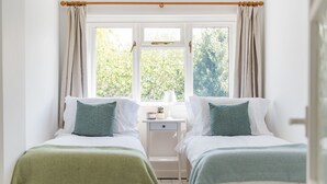 Un dormitorio con dos camas, una mesita de noche y una ventana con cortinas.