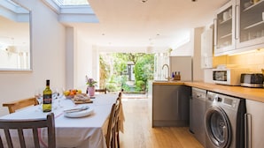 Una cocina moderna con comedor, lavadora y vistas a un jardín.