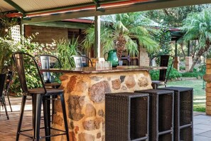 Eine Steintheke mit Barhocker, ein grüner Krug und ein Grill.