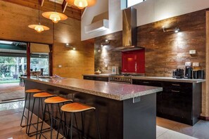 A modern kitchen with a large island, bar stools, and a red accent wall.