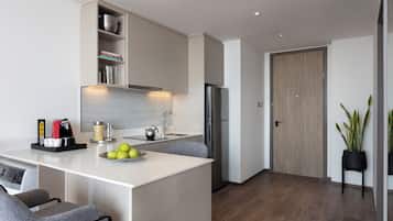A modern kitchen with a central island, built-in appliances, and a wooden door.
