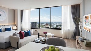 A modern hotel room with a large window, a bed, a sofa, a dining table, and a TV. - Ascott Embassy Sathorn Bangkok (Bangkok)