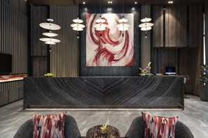 A modern reception area with a marble reception desk, a large abstract painting, and a seating area with patterned cushions. - Ascott Embassy Sathorn Bangkok (Bangkok)
