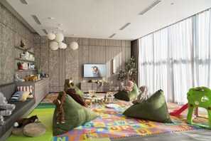 A living room with a sofa, green cushions, a play mat, and a television. - Ascott Embassy Sathorn Bangkok (Bangkok)