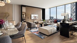 A modern living room with a large TV, seating, a dining area, and a view of the city. - Ascott Embassy Sathorn Bangkok (Bangkok)