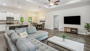 A modern living room with a sectional sofa, a dining area, and a kitchen. - Beautiful Pet Friendly Home With Private Pool - Minutes To Navarre Beach - Fast WiFi (Navarre)