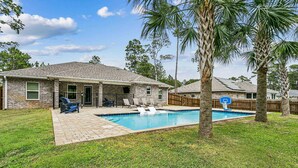A residential property with a swimming pool, a patio with chairs, and a wooden fence. - Beautiful Pet Friendly Home With Private Pool - Minutes To Navarre Beach - Fast WiFi (Navarre)