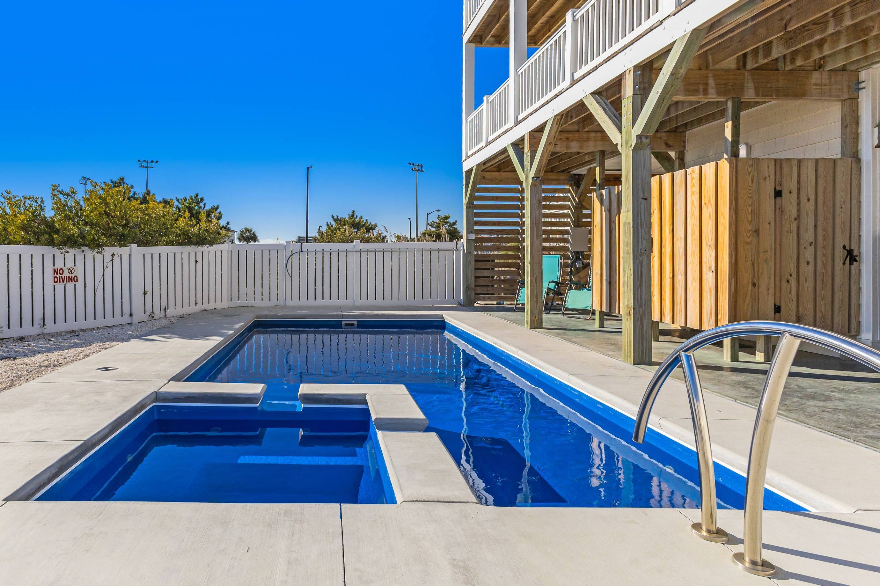 A swimming pool with a wooden deck and a white fence.