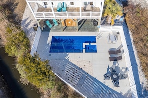 An aerial view of a pool area with a deck, lounge chairs, and a small building with a deck. - Private Saltwater Pool (Heating Optional), With Excellent Ocean Views Only 2 Blocks From the Beach (Oak Island)