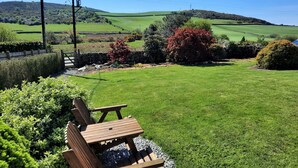 A grassy outdoor area with a wooden bench and picnic table, surrounded by well-maintained hedges and trees. - Croftdean -  a house that sleeps 6 guests  in 3 bedrooms (Dalbeattie)