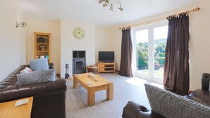 A living room with a sofa, a wooden coffee table, a television, and a fireplace. - Croftdean -  a house that sleeps 6 guests  in 3 bedrooms (Dalbeattie)